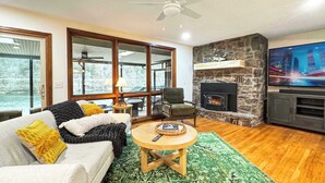 Ein gemütliches Wohnzimmer mit Kamin, Fernseher und Blick ins Freie.