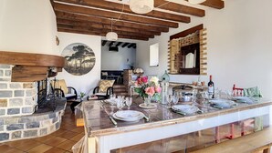 A rustic dining area with exposed wooden beams, a stone fireplace, and a brick wall. - Gîte Le Karrdi (10 pers) in Brittany, ideal for families. Pets welcome! (Landavran)