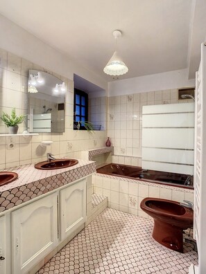 A bathroom with a large mirror, two sinks, a bathtub, and a toilet. - Gîte Le Karrdi (10 people) in Brittany, ideal for families. Pets allowed! (Landavran)