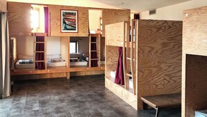Une chambre avec des lits superposés, une fenêtre avec des rideaux et un tableau encadré au mur.