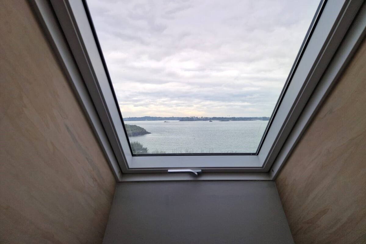 A skylight with a view of a body of water and distant land.