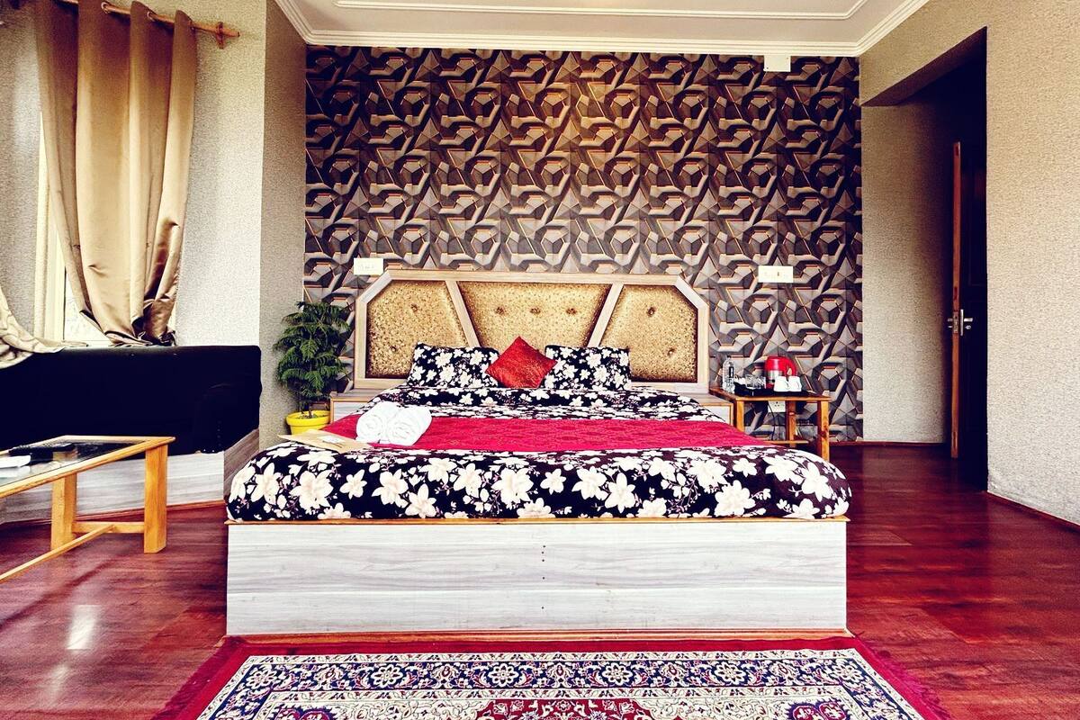 A bedroom with a bed, a nightstand, a potted plant, and a patterned wall.