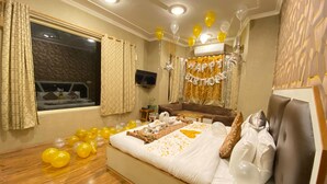 Un dormitorio con una cama grande, un televisor montado en la pared y globos en el suelo.