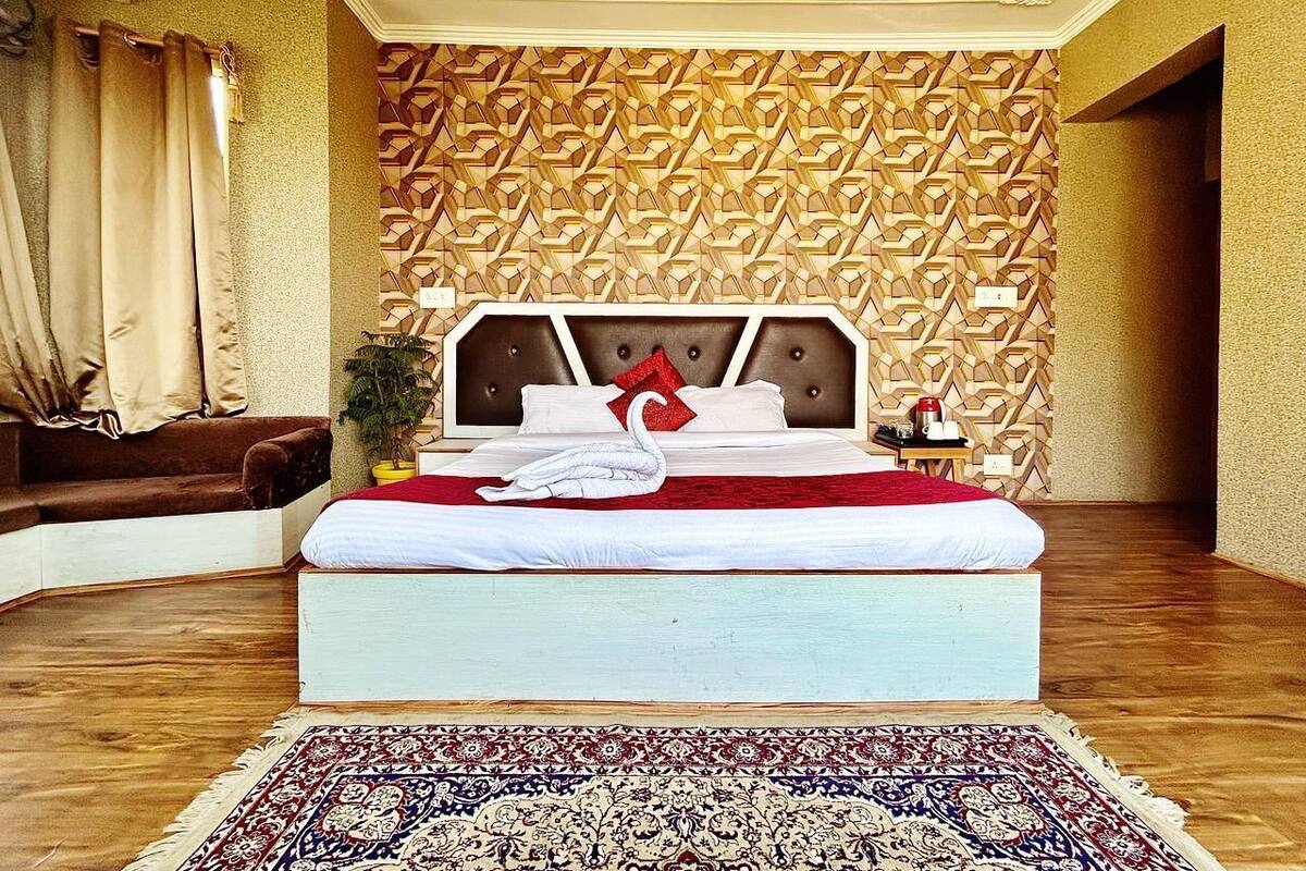 A bedroom with a bed, a red and white swan decoration, a patterned wall, and a wooden floor.