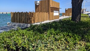 A wooden structure with a white sign, located near a body of water and a tree. - 110sqm T4 house with enclosed garden, 1500m from the beach (Port-la-Nouvelle)