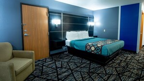 Una habitación de hotel con cama, mesita de noche, silla y puerta.