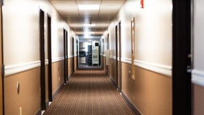Un pasillo de hotel con alfombra estampada, paredes color beige y puertas a ambos lados.