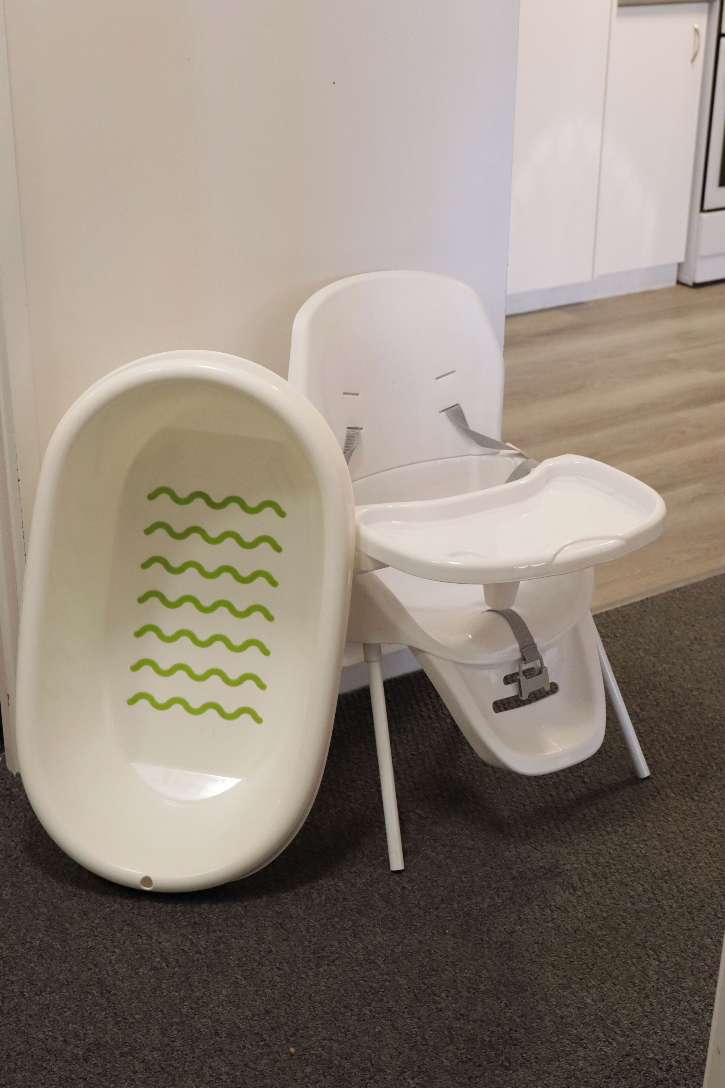 Des toilettes portables blanches, avec des motifs ondulés verts sur le siège, une chaise blanche et un meuble blanc en arrière-plan.