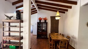 Un comedor con mesa y sillas de madera, un mueble con puertas de vidrio y una lámpara colgante.