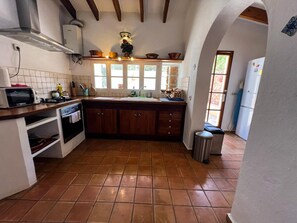 A kitchen with a tiled floor, wooden cabinets, a sink, a stove, and a microwave. - HOUSE WITH POOL AND ANNEX NEAR THE BEACHES OF ES PUJOLS (ET-41113) (Formentera)