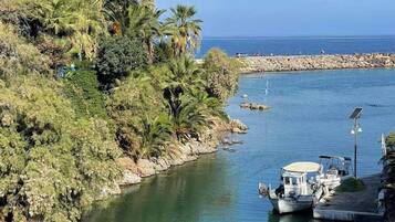 A calm river with boats docked, surrounded by lush greenery and a rocky shoreline.