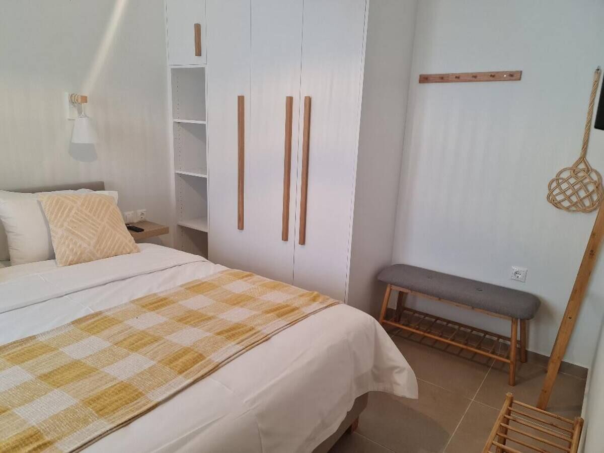 Une chambre à coucher comprenant un lit, un banc, une armoire et une étagère fixée au mur.