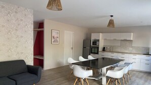 A modern kitchen with white cabinets, a black countertop, and a stainless steel refrigerator. - Villa with sea access and spa (Saint-Vincent-sur-Jard)