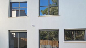 A modern two-story house with large windows, a sliding glass door, and a hot tub in the foreground. - Villa with sea access and spa (Saint-Vincent-sur-Jard)