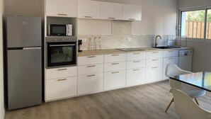 A modern kitchen with white cabinets, stainless steel appliances, and a wooden countertop. - Villa with sea access and spa (Saint-Vincent-sur-Jard)