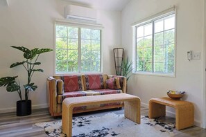 A living room with a sofa, a coffee table, and two potted plants. - Topanga 1BR Bungalow | Canyon Views + Loft | C&C (Topanga)