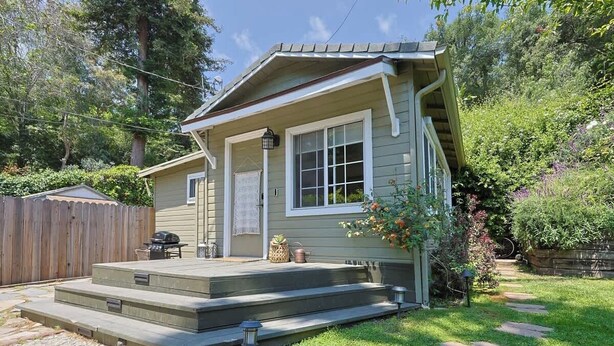 Ein Haus mit Veranda, einer kleinen Terrasse und einem Weg zum Eingang.
