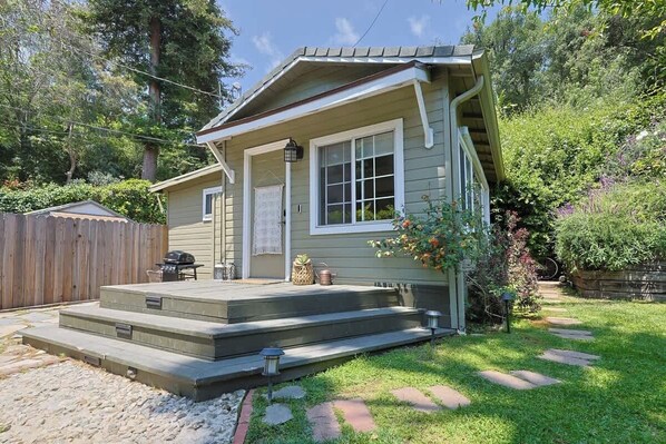 A house with a front porch, a small deck, and a pathway leading to the front door.