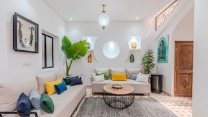 A modern living room with a sofa, coffee table, and large plant. - Riad Dar Amarena - Exclusif - BreakFast (Marrakech)