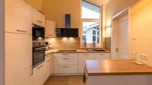 Eine moderne Küche mit weißen Schränken, einem Einbauofen, einer Mikrowelle und einem großen Fenster für natürliches Licht.