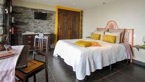 A bedroom with a bed, a desk, and a stone wall.