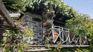 A rustic stone building with a wooden fence and a small waterfall feature.