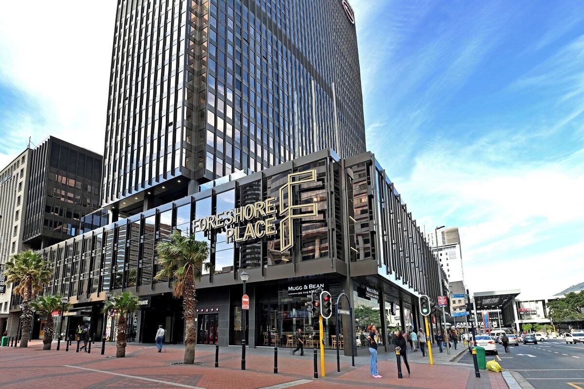 A modern building with a prominent 'FORESHORE PLACE' sign, featuring a glass facade and a ground-level entrance.