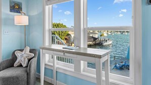 A room with a view of a marina, a starfish pillow on a chair, a lamp, and a table with a notebook. - Mermaid Manor ~ Waterfront Haven w/ Hot Tub & Dock (Marathon)