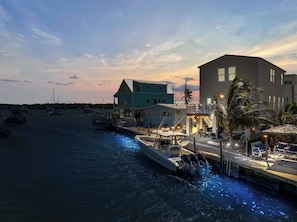 A waterfront property with a dock, boats, and a building with a balcony.