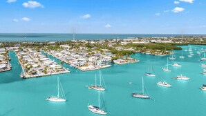 An aerial view of a marina with numerous boats docked, surrounded by residential buildings and greenery. - Mermaid Manor ~ Waterfront Haven w/ Hot Tub & Dock (Marathon)