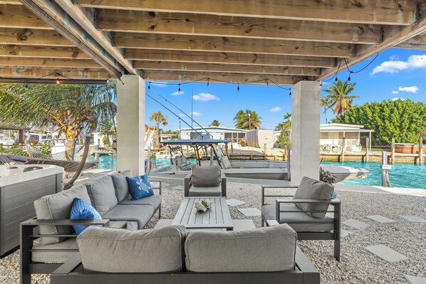An outdoor seating area with a pool, lounge chairs, and a wooden pergola.