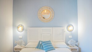 Une chambre à coucher comprenant un lit, deux tables de chevet, un miroir fixé au mur et deux appliques murales.
