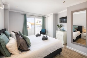 A modern bedroom with a large bed, a dresser, a mirror, and a TV on the wall. - Casa Milhafre - Apartment overlooking Benagil Beac (Benagil)