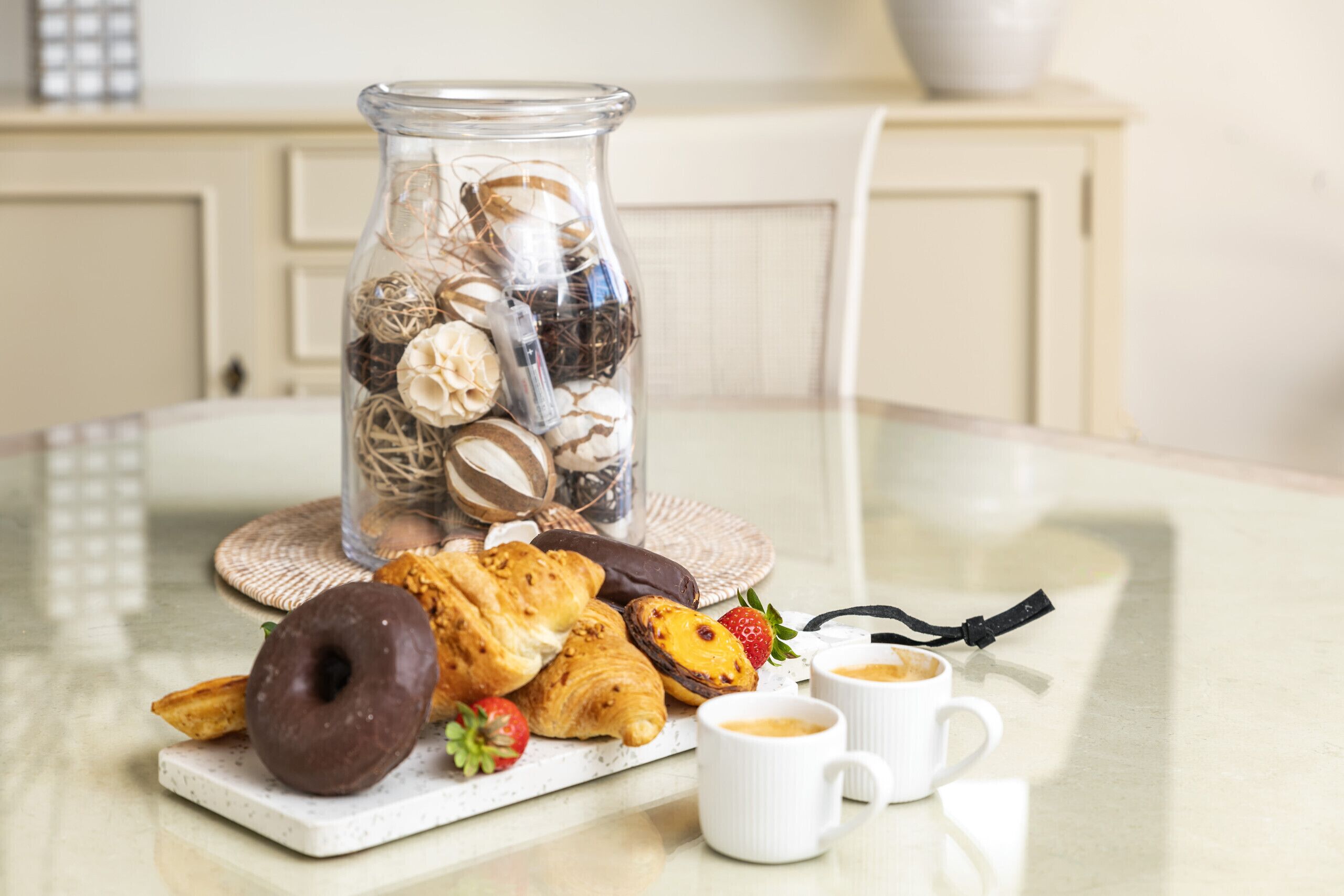 A glass jar filled with decorative items and pastries on a table.