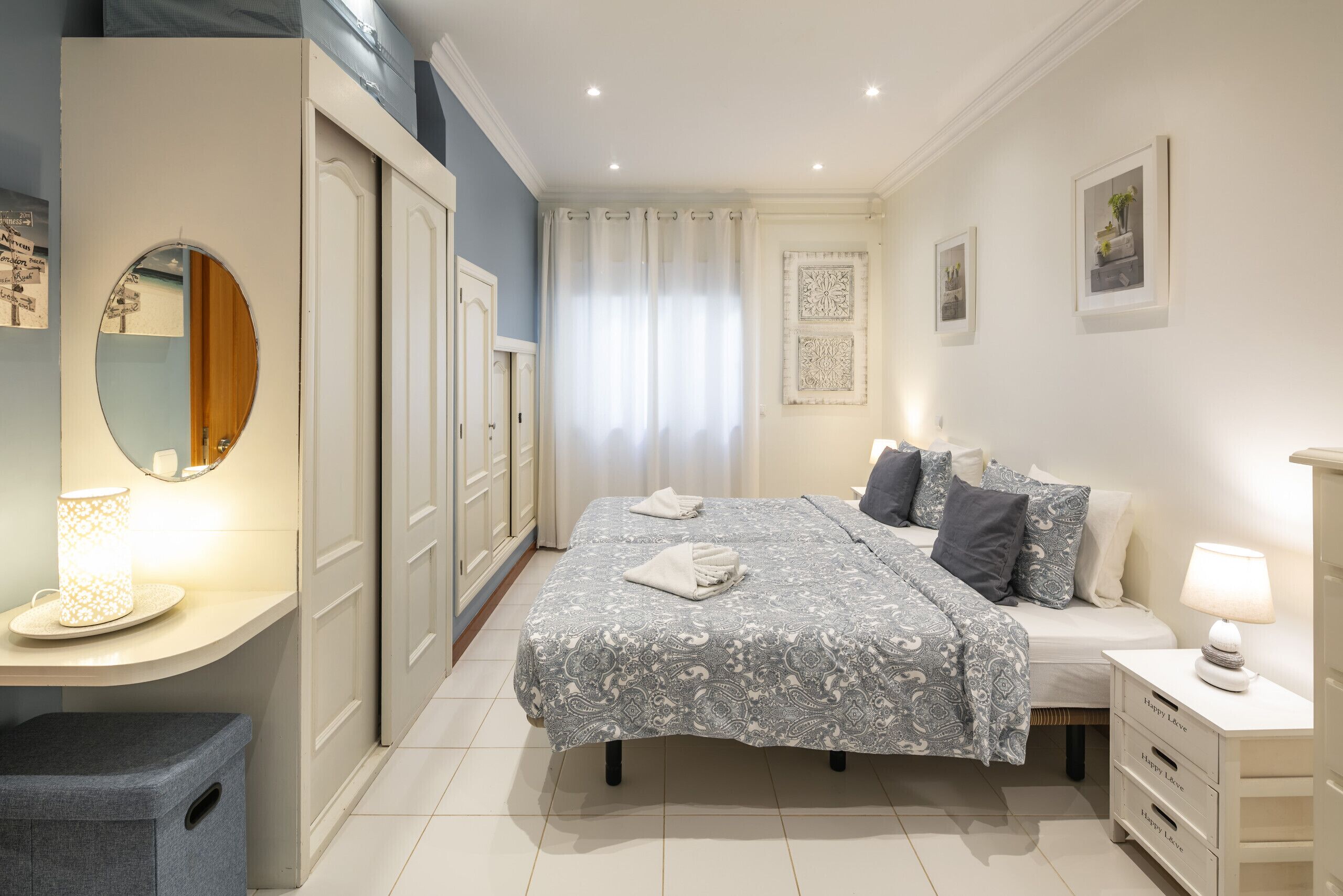 Une chambre à coucher avec un lit, des tables de chevet, un miroir et une armoire.
