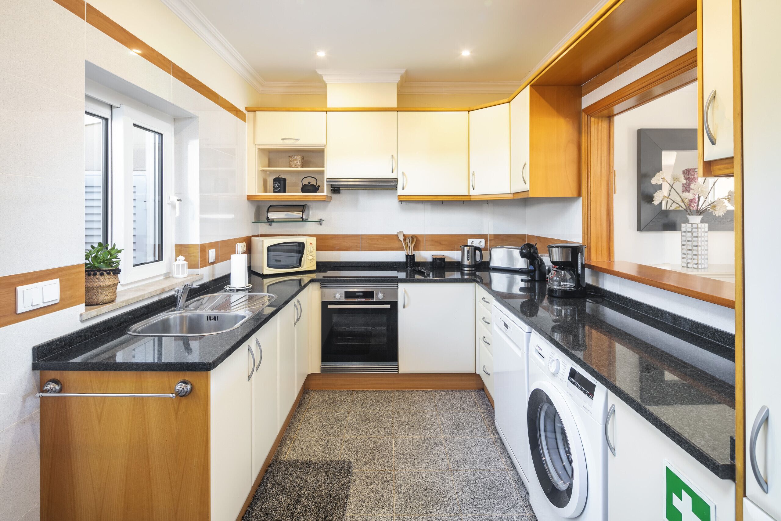 A compact kitchen with a washing machine, a microwave, and a sink.