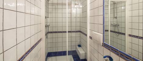 A bathroom with a glass-enclosed shower, a white sink, and a mirror.