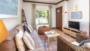 A living room with a sofa, bean bag, coffee table, TV stand, and wicker furniture. - 33 Terraços de Benagil (Casa Madeleina) (Benagil)