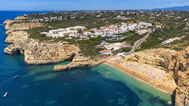 An aerial view of a coastal town with a beach, rocky cliffs, and residential buildings. - 33 Terraços de Benagil (Casa Madeleina) (Benagil)