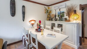Un comedor con una mesa blanca, sillas blancas y un aparador blanco decorado.