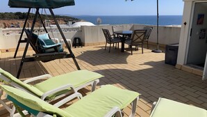 A terrace with sun loungers, a swing, a table with chairs, and a view of the sea. - 22 Terraços de Benagil (Casa Liz) (Benagil)