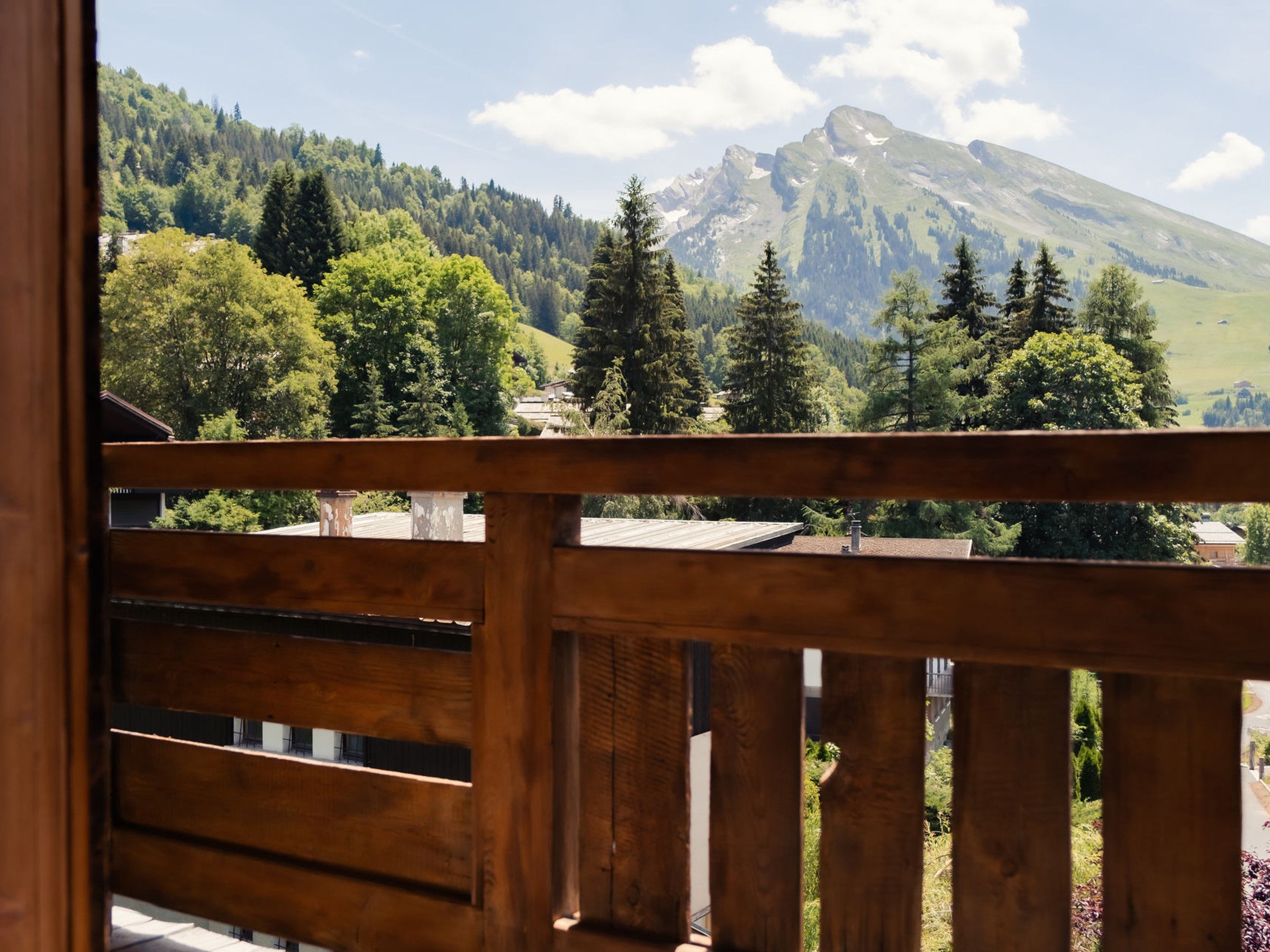 Un balcon en bois offrant une vue sur une montagne et une forêt.