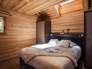 A wooden-paneled bedroom with a bed, a nightstand, and a window.