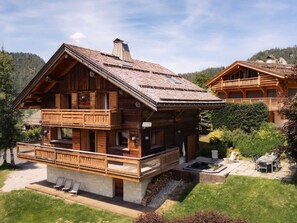 A wooden chalet with a balcony, a hot tub, and a dining area.