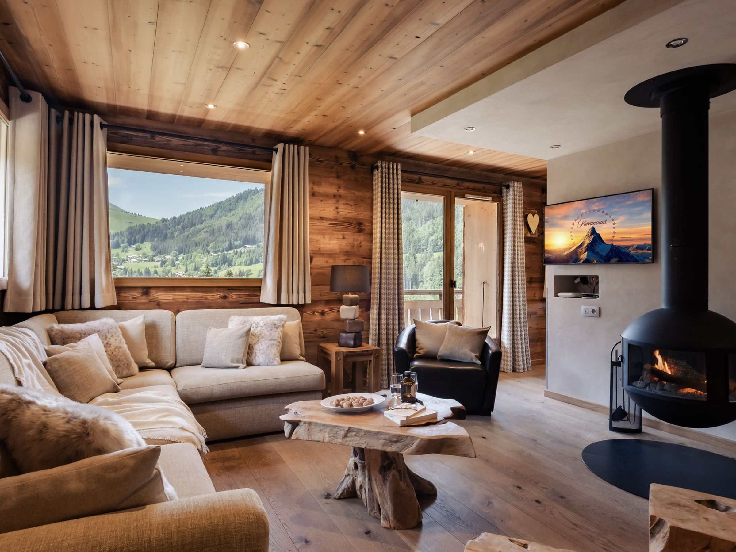 A cozy living room with a sofa, a coffee table, a fireplace, and a view of the outdoors.