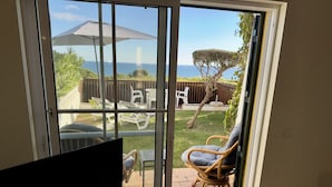 A room with a sliding glass door leading to a patio with outdoor furniture and a view of the sea. - 06 Terraços de Benagil (Casa Rosa Azul) (Benagil)