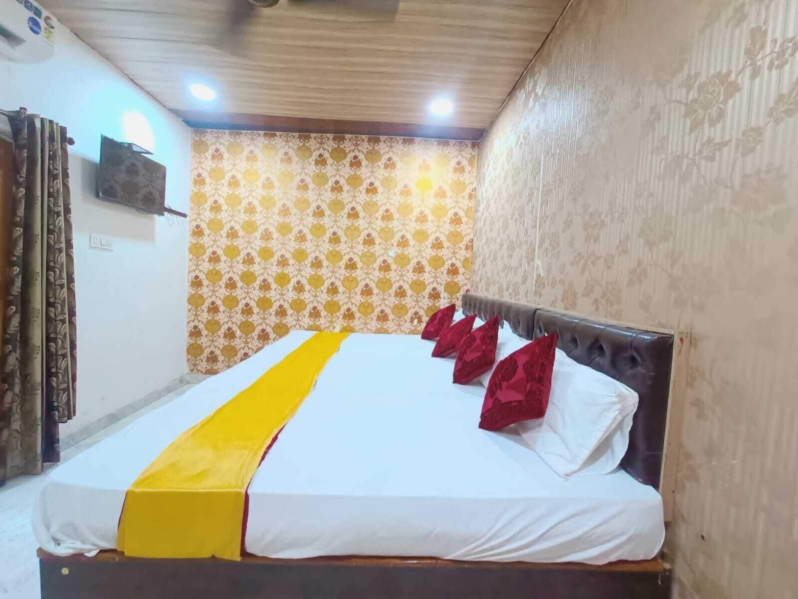 A bed with a white and yellow bedspread, red pillows, and a wooden headboard.