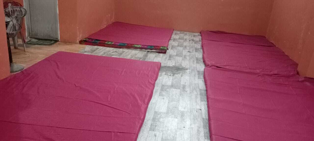A room with a tiled floor and two beds covered with pink sheets.