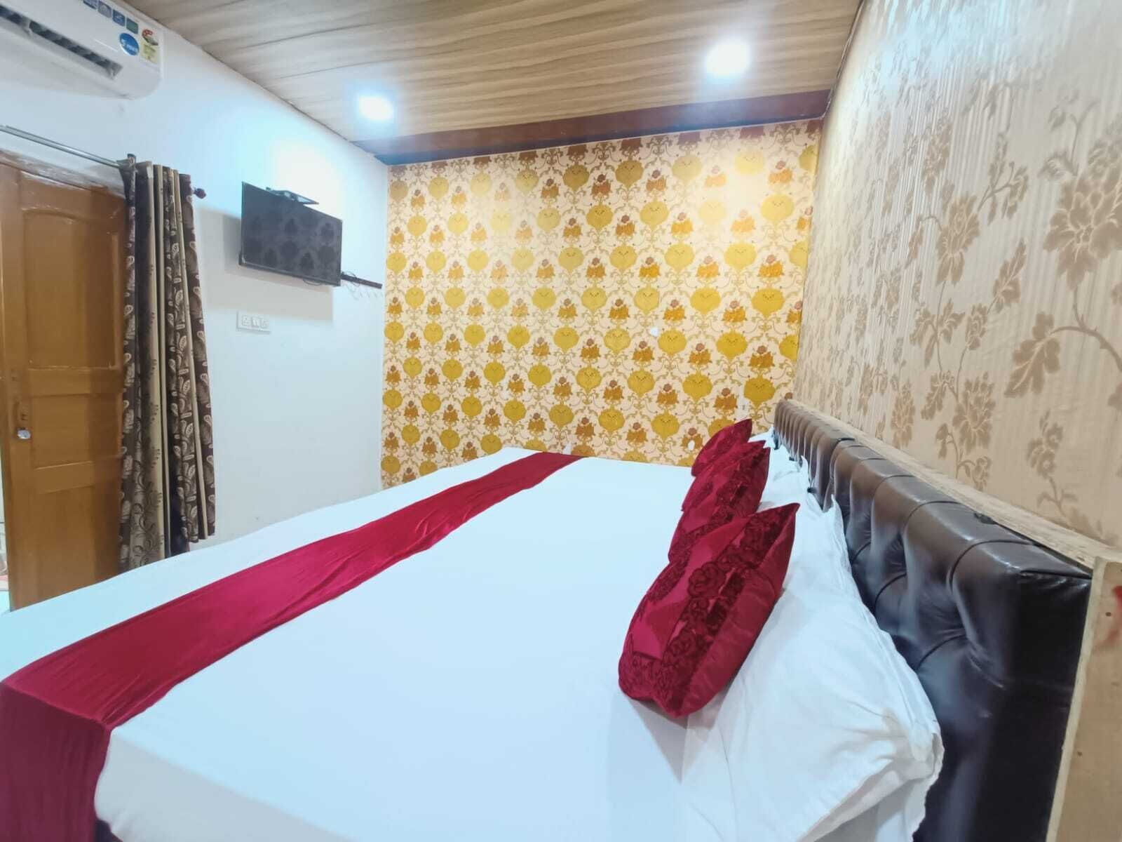 A hotel room with a bed, curtains, a television, and patterned wallpaper.