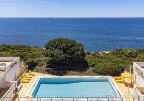 Ein Schwimmbecken mit Blick auf das Meer und einem Baum im Vordergrund.